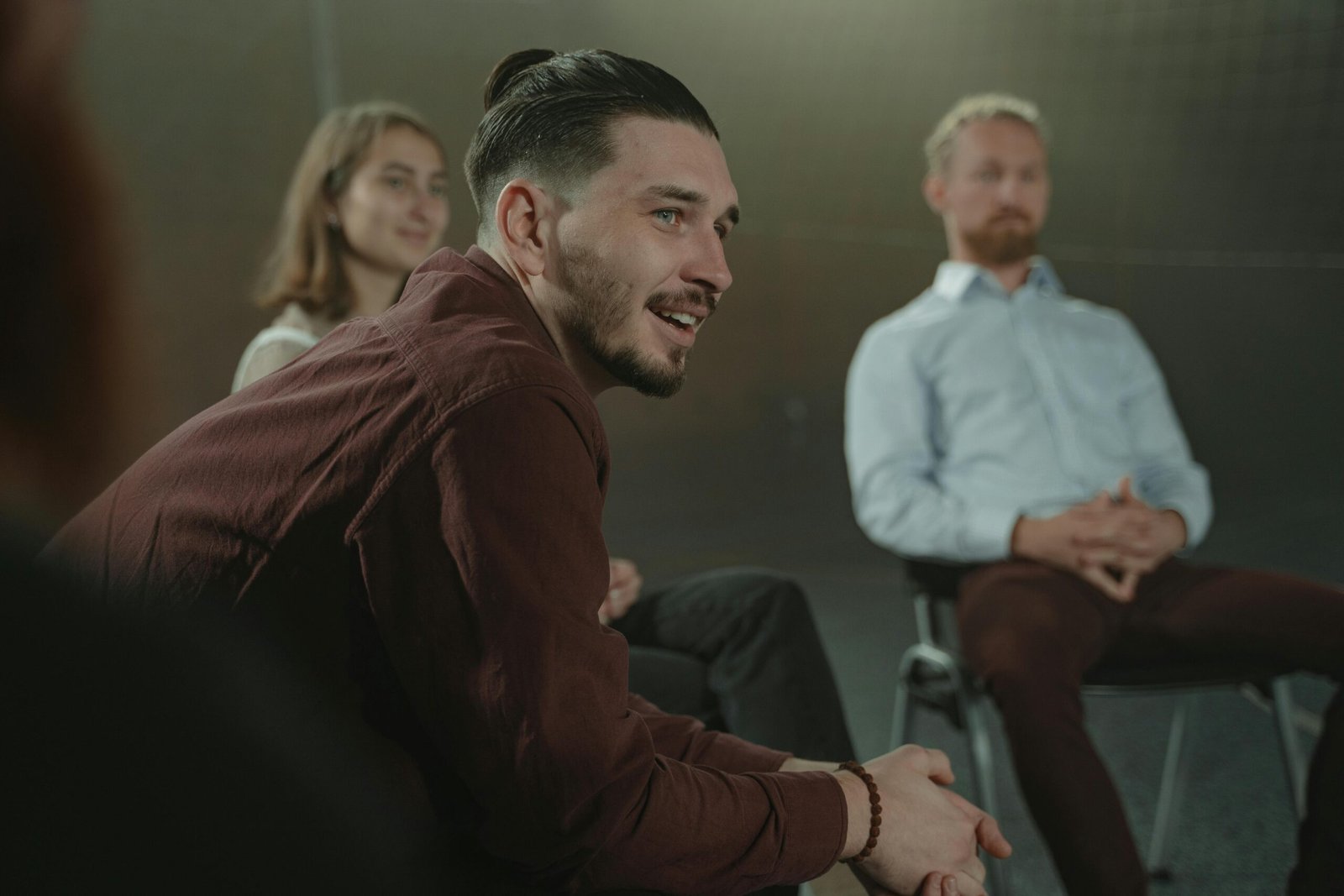 Adults sitting in a circle engaged in a group discussion indoors.